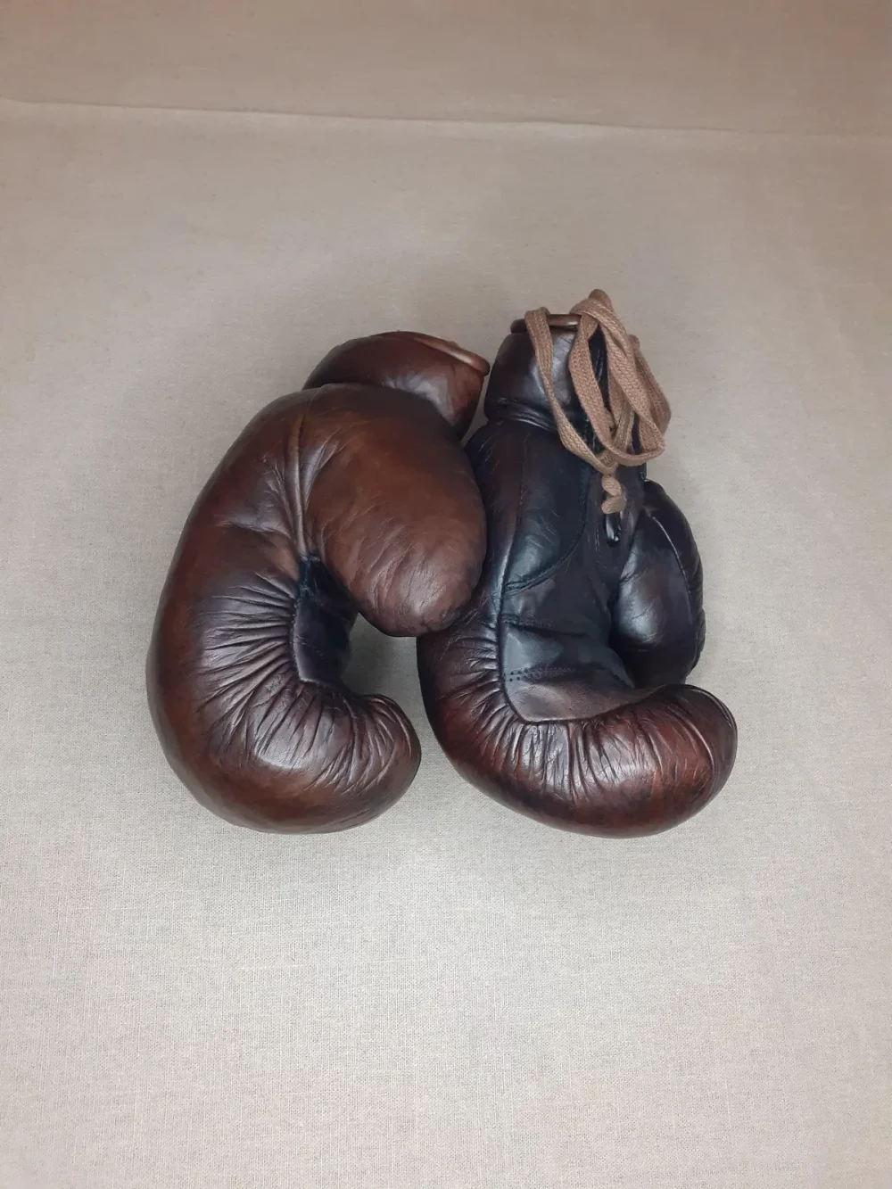 Gants de boxe marron vintage, cuire pleine fleur patiné à la main. Garnissage en fibres naturel, fermeture : lacet en coton. Élégante et stylée, cette paire de gants de boxe vintage fabriquée à l'ancienne servira à donner un aspect authentique à votre décoration. 