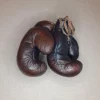 Gants de boxe marron vintage, cuire pleine fleur patiné à la main. Garnissage en fibres naturel, fermeture : lacet en coton. Élégante et stylée, cette paire de gants de boxe vintage fabriquée à l'ancienne servira à donner un aspect authentique à votre décoration. 