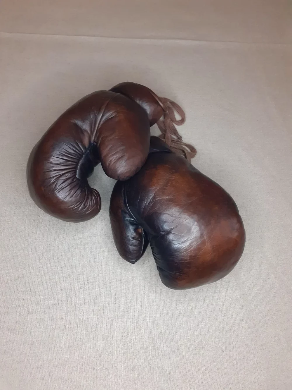 Gants de boxe marron vintage, cuire pleine fleur patiné à la main. Garnissage en fibres naturel, fermeture : lacet en coton. Élégante et stylée, cette paire de gants de boxe vintage fabriquée à l'ancienne servira à donner un aspect authentique à votre décoration. 