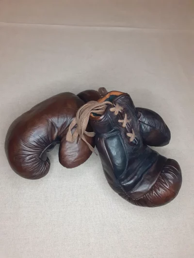 Gants de boxe marron vintage, cuire pleine fleur patiné à la main. Garnissage en fibres naturel, fermeture : lacet en coton. Élégante et stylée, cette paire de gants de boxe vintage fabriquée à l'ancienne servira à donner un aspect authentique à votre décoration. 