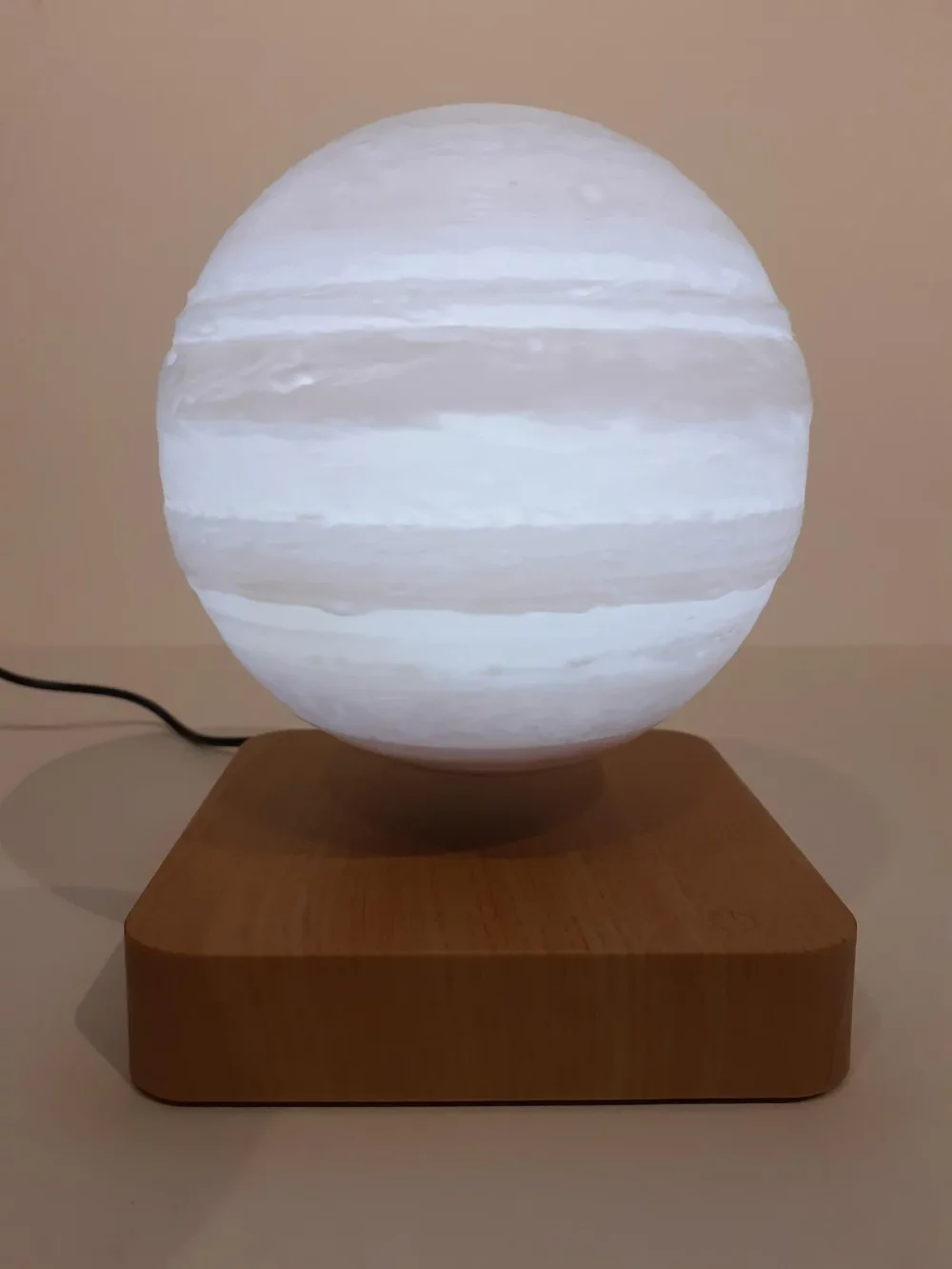 Ce globe représentant Jupiter en lévitation au dessus de son socle en bois émerveillera à coup sûr ses observateurs. Il diffuse par rétro-éclairage interne une lumière radiale tamisée avec 3 coloris au choix