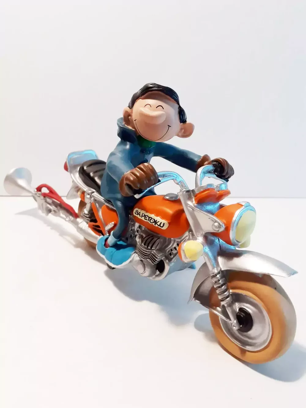 Figurine de Gaston avec sa moto. Statuette de collection en résine sculptée et peinte à la main. Ne convient pas aux enfants de moins de 14 ans.