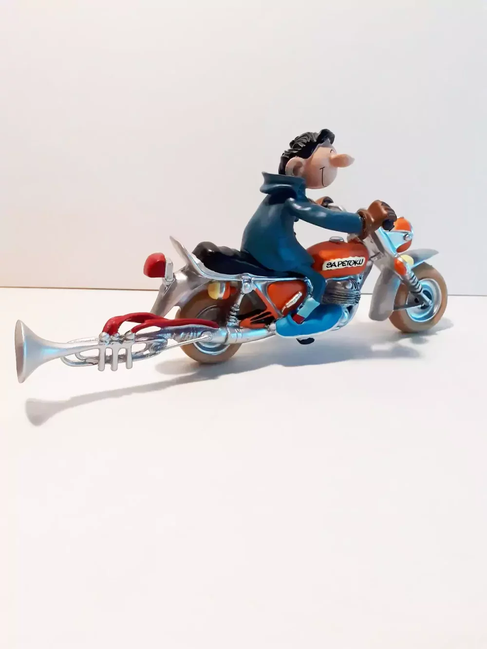 Figurine de Gaston avec sa moto. Statuette de collection en résine sculptée et peinte à la main. Ne convient pas aux enfants de moins de 14 ans.