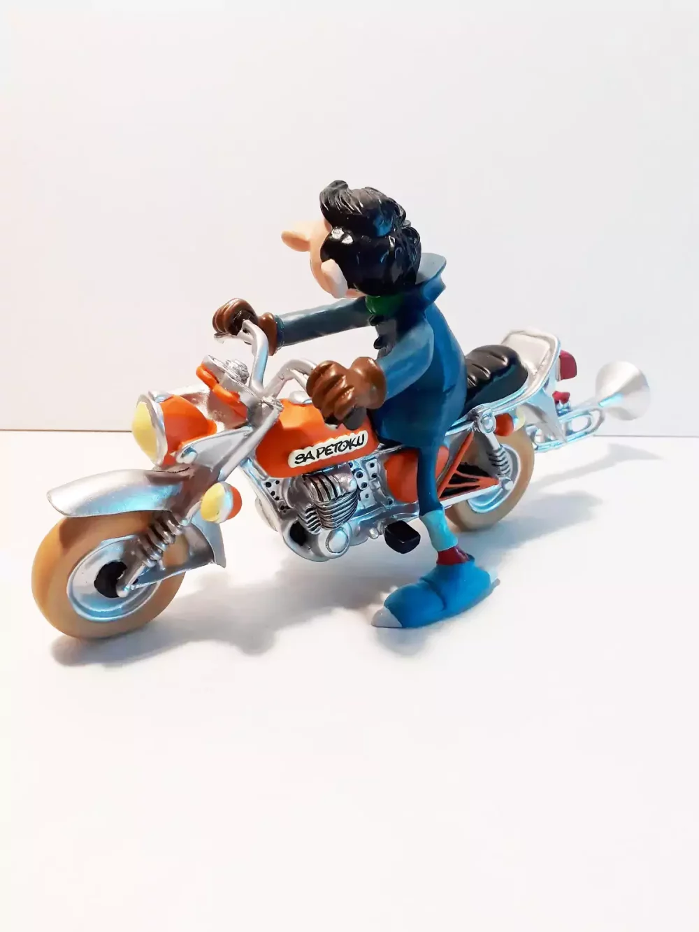 Figurine de Gaston avec sa moto. Statuette de collection en résine sculptée et peinte à la main. Ne convient pas aux enfants de moins de 14 ans.